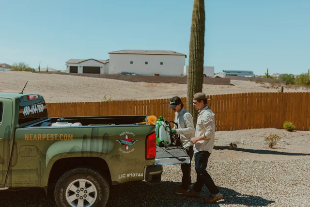 NEARPEST team beside the olive and gold branded pickup in a desert yard