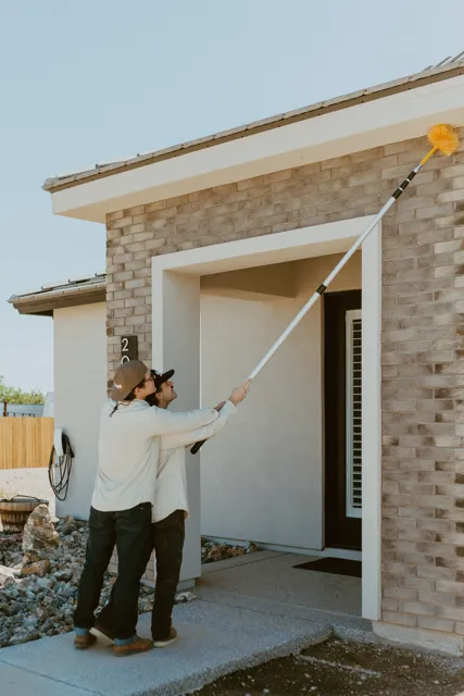 NEARPEST team removing webs around a home entry with a long-handled duster