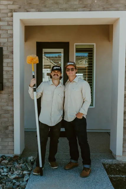 The two NEARPEST owners standing together at a home entry with a duster