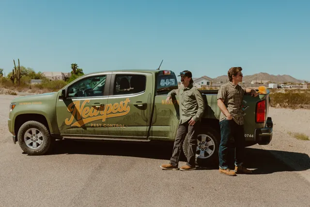 The two NEARPEST owners standing beside their branded pickup