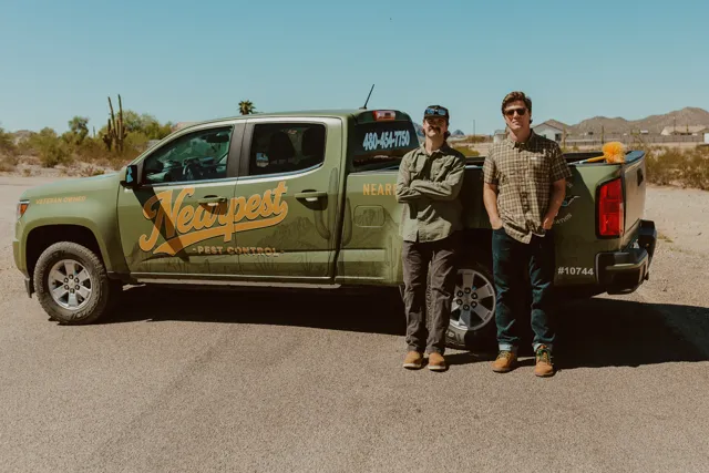 The two NEARPEST owners standing beside their branded pickup
