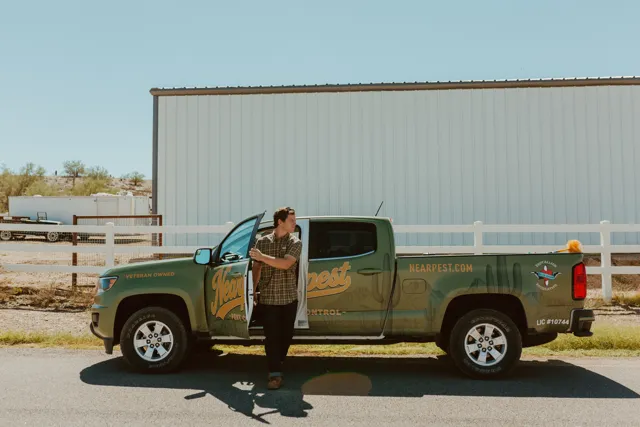 NEARPEST team member beside the branded pickup outside a metal building