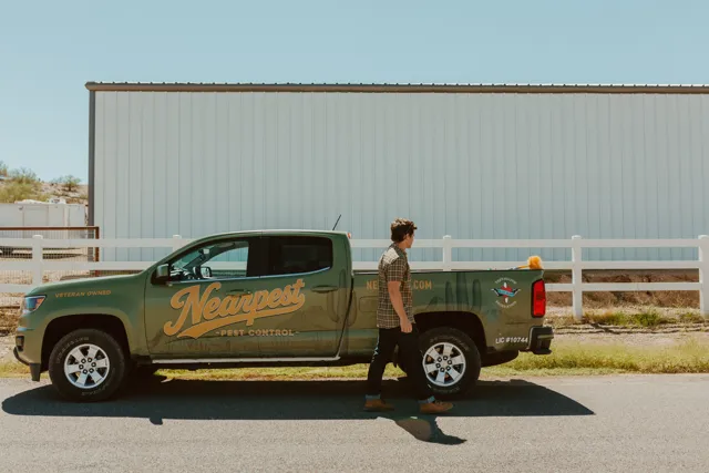 NEARPEST team member beside the branded pickup outside a metal building