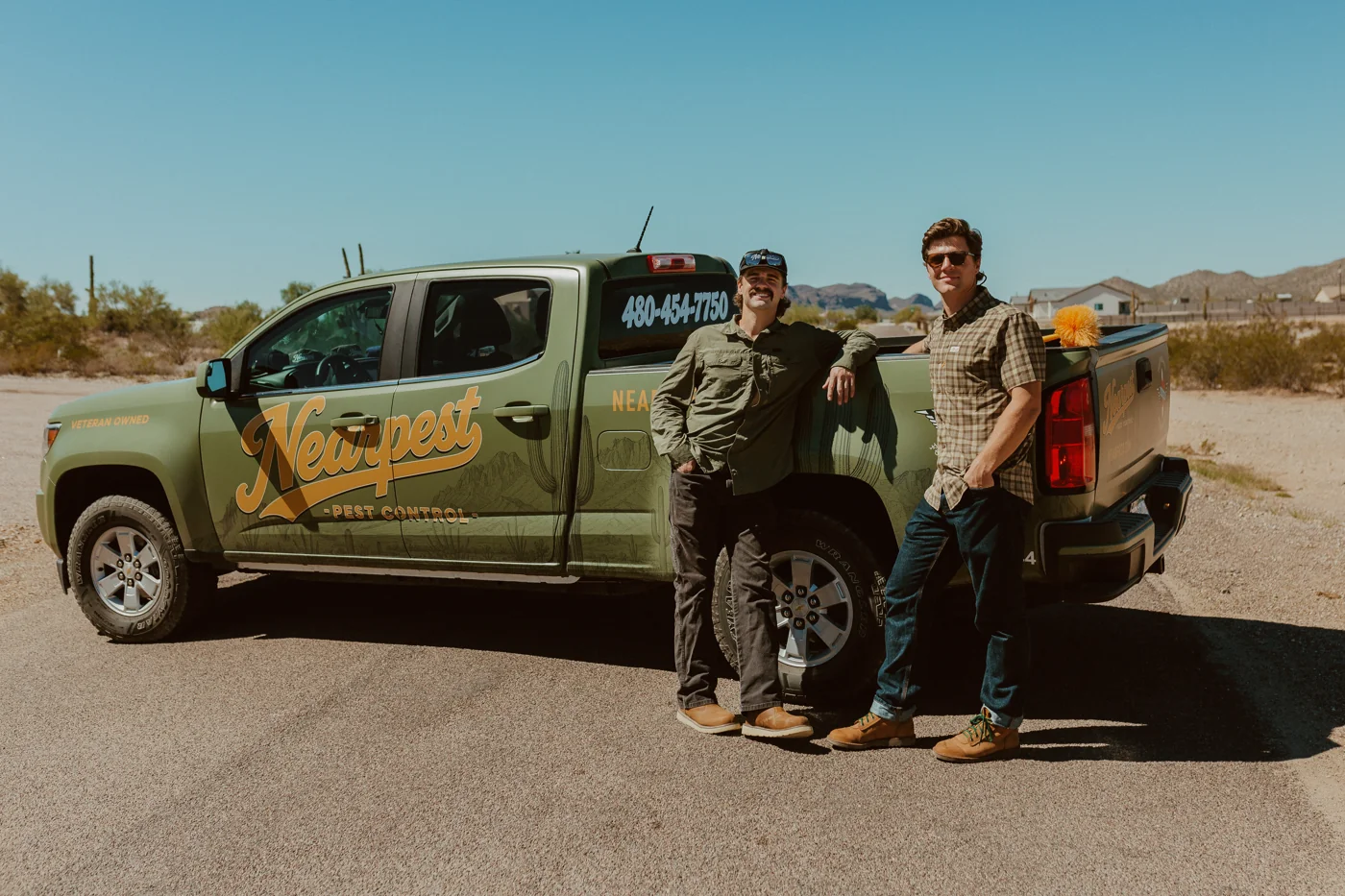Ryland and Keegan beside the olive and gold NEARPEST pickup truck